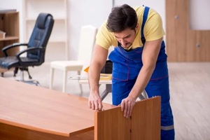 young male carpenter repairing desk in the office