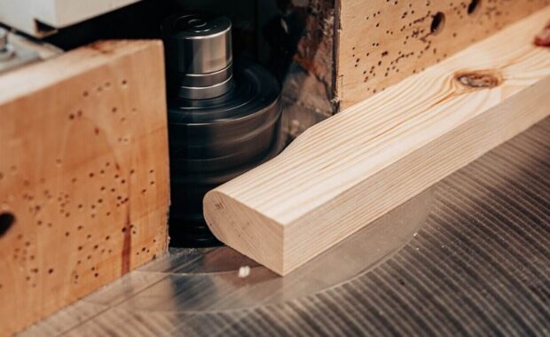 close-up of wood being shaped on spindle moulder at custom millwork company studio