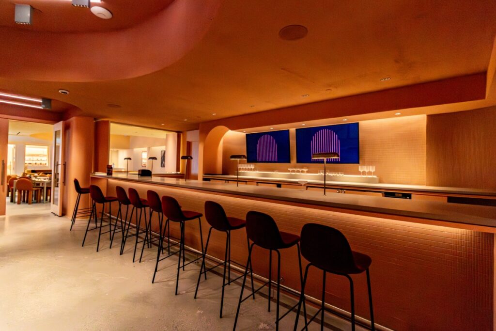 Long bar seating area with custom bar millwork and lighting at Manifest CAW in Washington, DC.