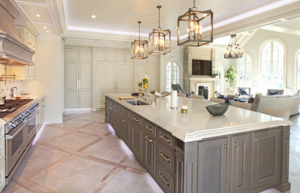 An open-concept luxury kitchen and living area featuring a long, dark-grey island with a white marble countertop and integrated sink.