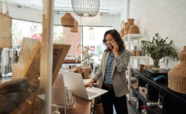 Smiling Asian woman talking on a cellphone in her store