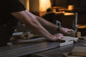 artisan working with a table saw in a dimly lit workshop