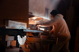 dedicated craftsman working with wood in a dimly lit workshop, highlighted by a beam of light